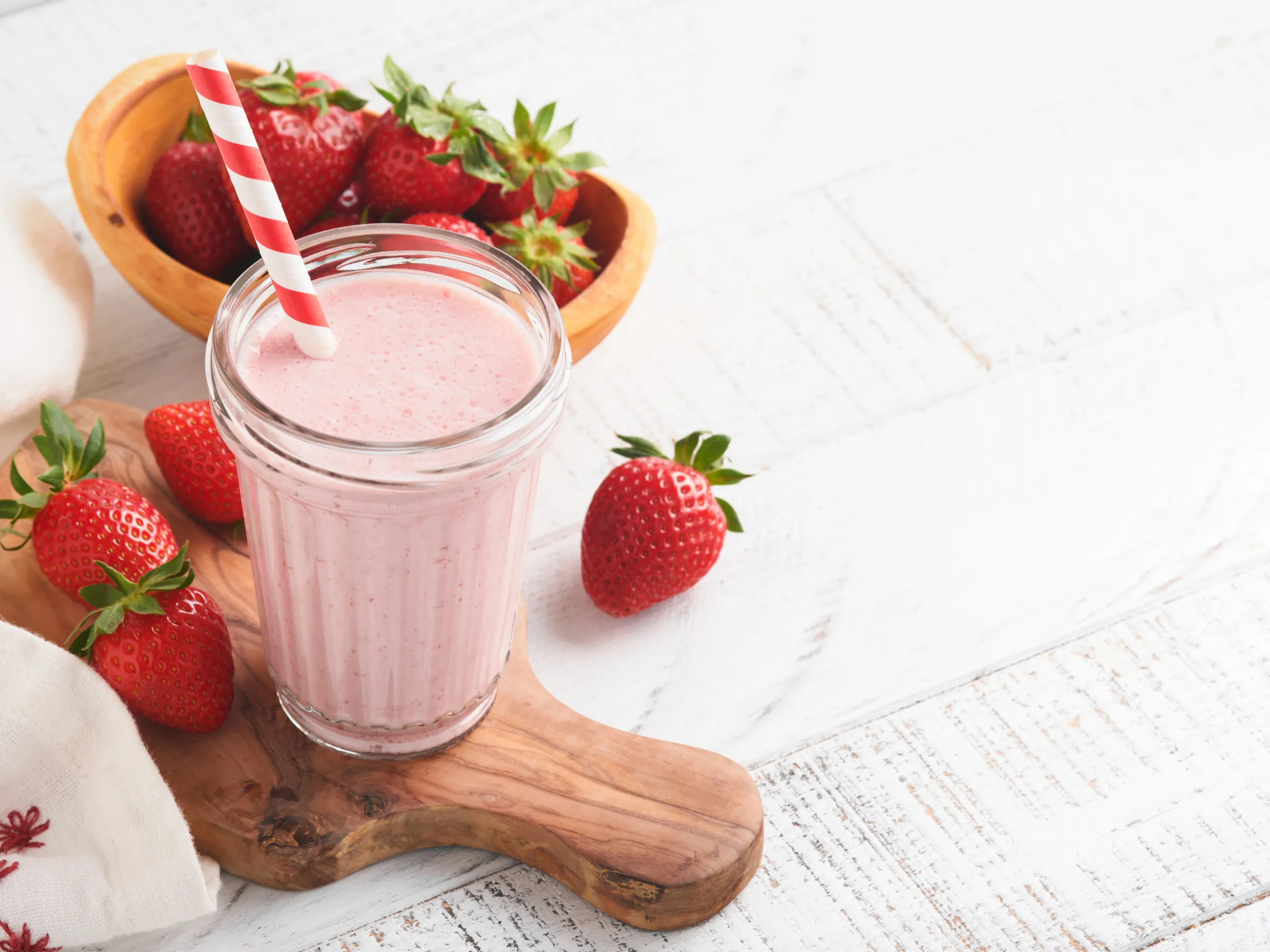 Strawberry smoothie in a glass with a striped straw